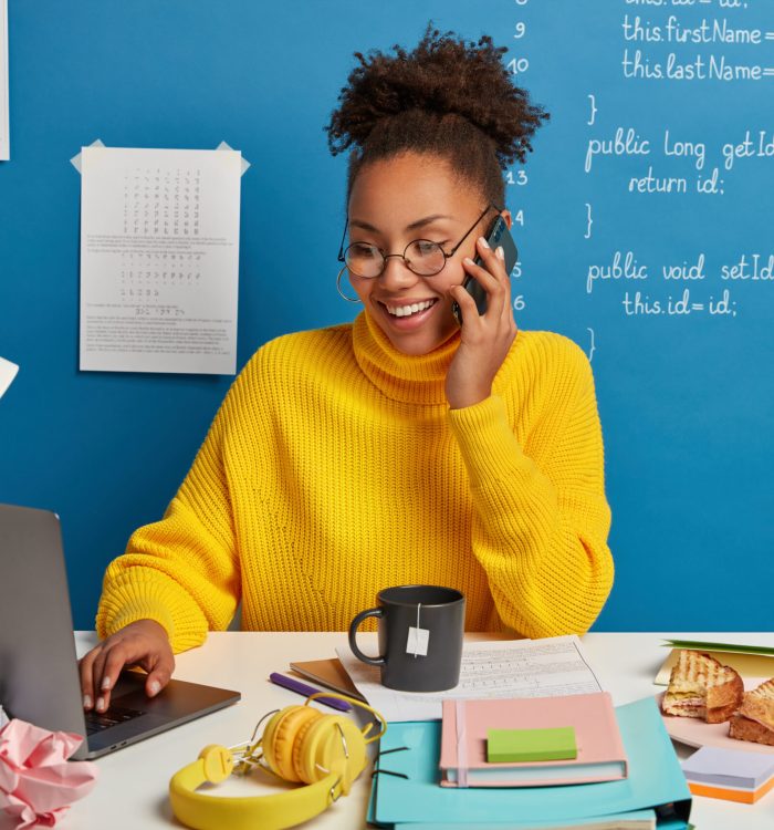 Professional web editor creats technical stucture of website, discusses some working issues via smartphone, wears spectacles, surfs internet on modern laptop. Digital technology for programming